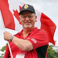 Bernie VanPelt, Team Captain for Team Canada, pictured at the 2022 World Championships in Switzerland. He is wearing official team apparel and holding the Canadian flag.