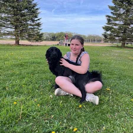 A girl and a dog cuddling on the grass
