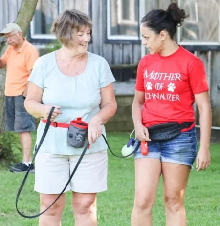 A dog trainer demonstrates how to use a leash by attaching it to the client